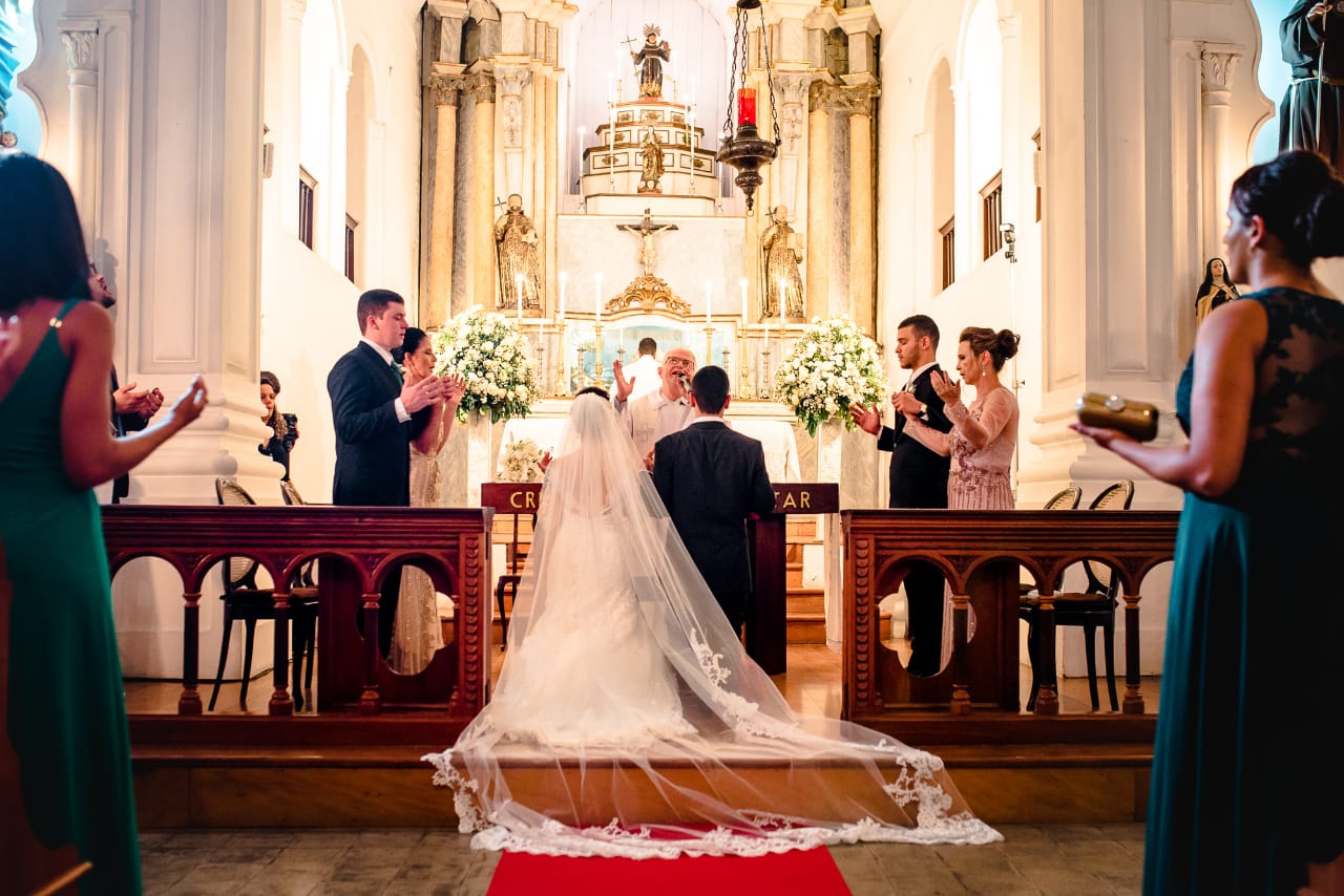 Visão ampla dos noivos no altar com madrinhas e padrinhos.